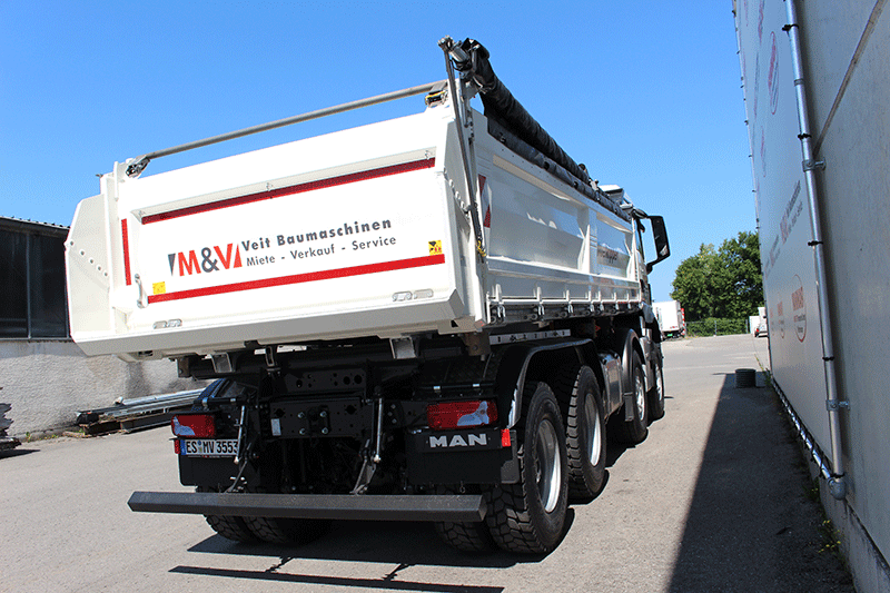 Heckansicht des MAN TGS 35.480 8x4 Kippers mit robuster Kippermulde, Rückleuchten und rot-weißer Warnmarkierung