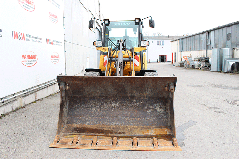 Die Frontansicht des Volvo Radladers L 25 zeigt das robuste Design, die leistungsstarke Schaufelaufnahme und die kompakte Bauweise für den Baustelleneinsatz.