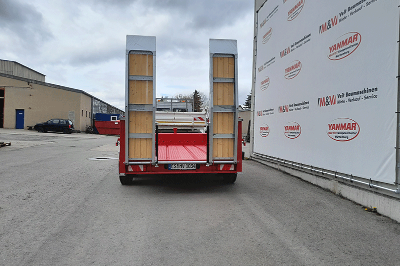 Heckansicht des Fliegl TTS 89 Tandemanhängers mit hochgestellten Auffahrrampen und stabiler Rahmenkonstruktion für den sicheren Maschinentransport.